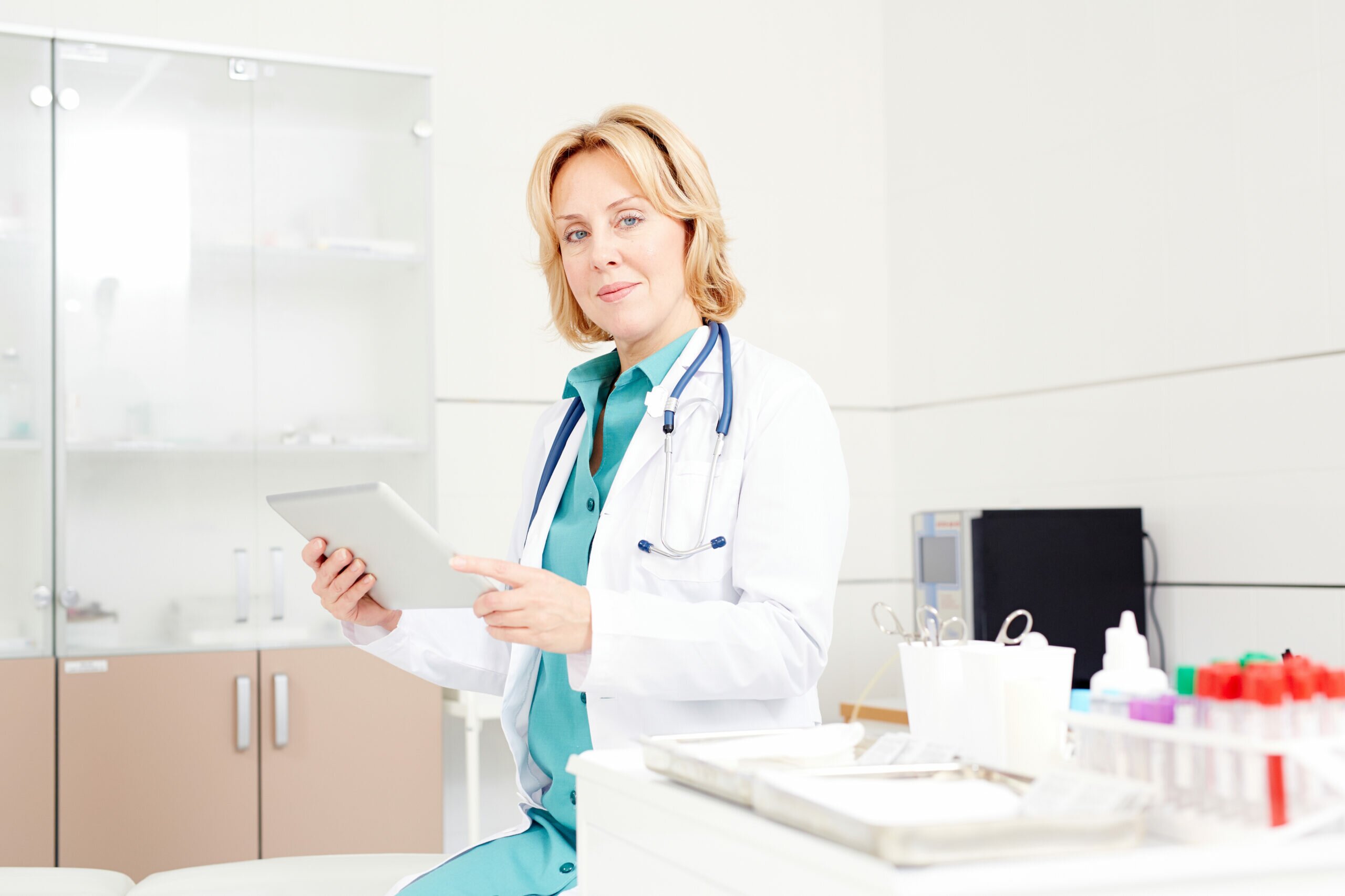 Modern doctor with touchpad working in the net in her office